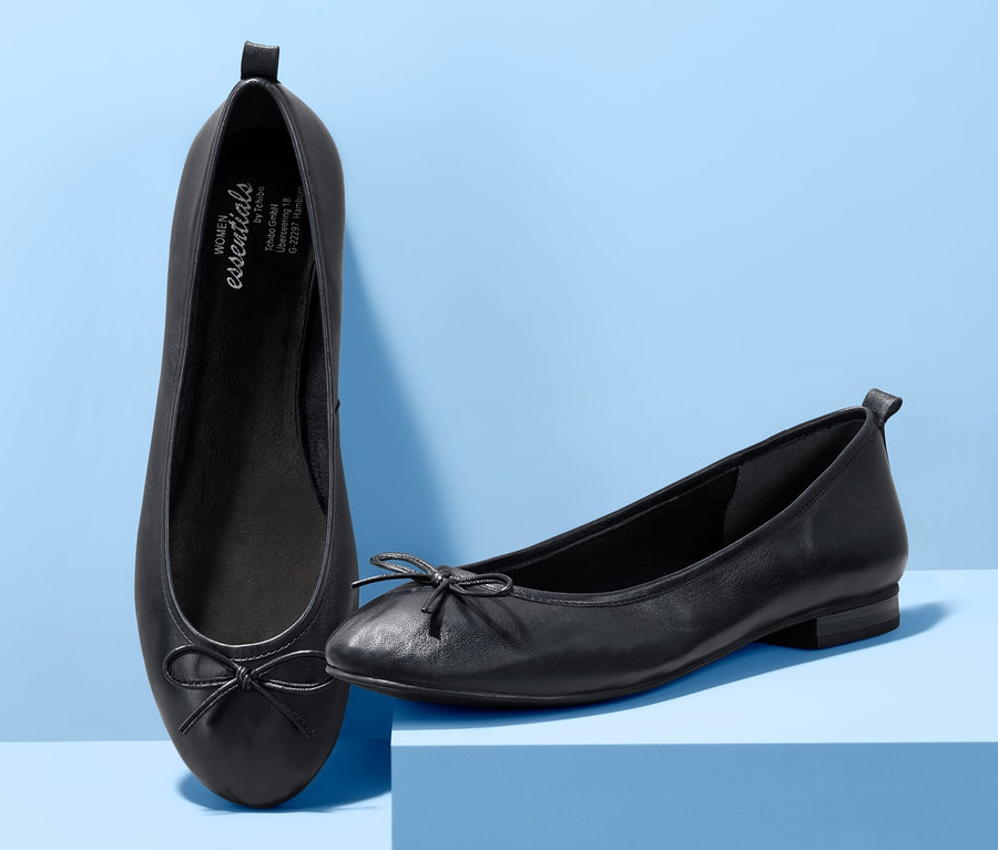 Zwei Leder-Ballerinas auf blauem Hintergrund.