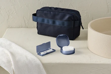 Auf dem Tisch liegen ein Aufbewahrungs-Set und eine dunkelblaue Kulturtasche.