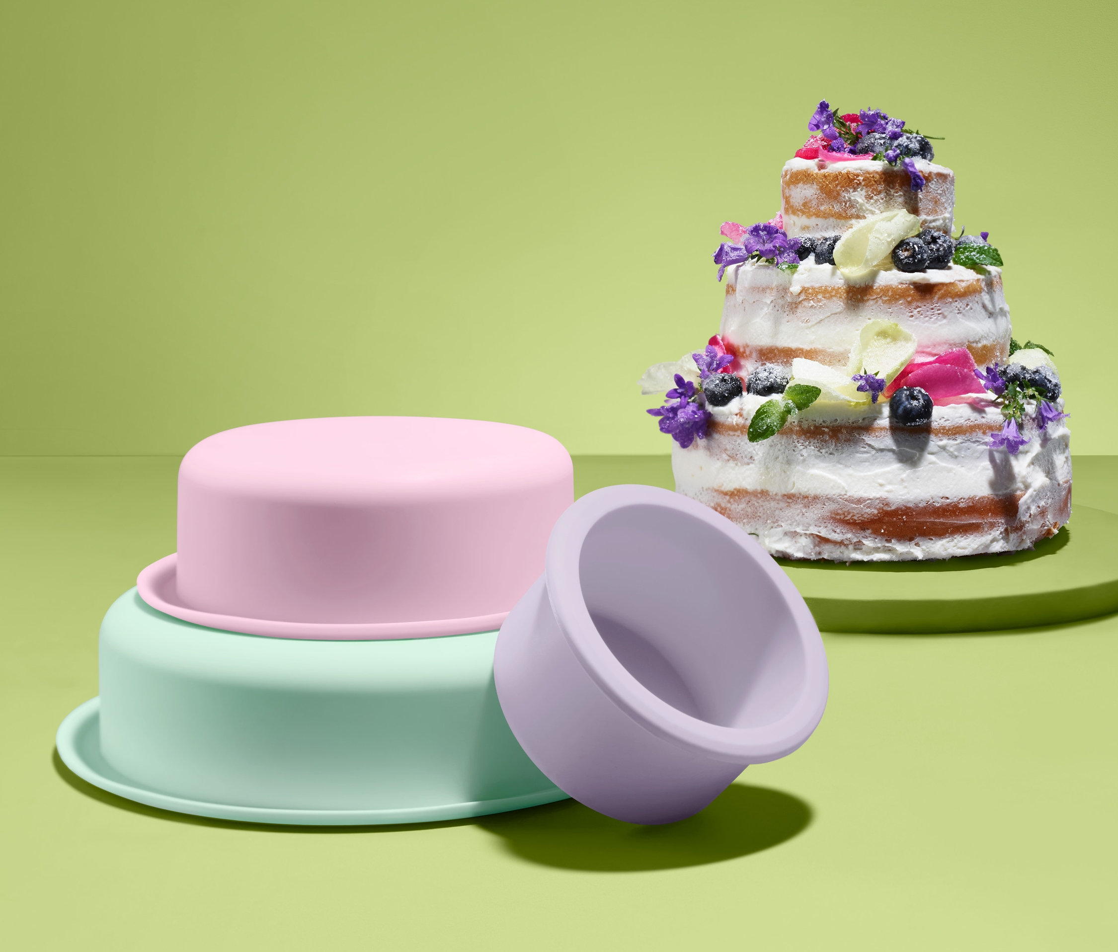 Ein mit Blumen dekorierter, mehrstöckiger Kuchen neben einem Tortenset.