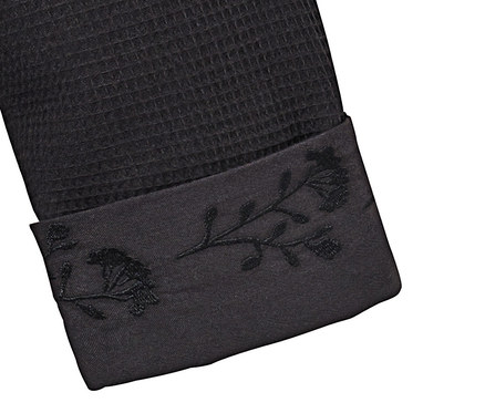 Detailansicht eines schwarzen Damen-Bademantels mit floraler Stickerei an der Manschette.