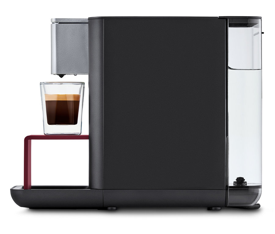 Qbo ESSENTIAL Dark Berry Kaffeemaschine mit einer Tasse Kaffee.