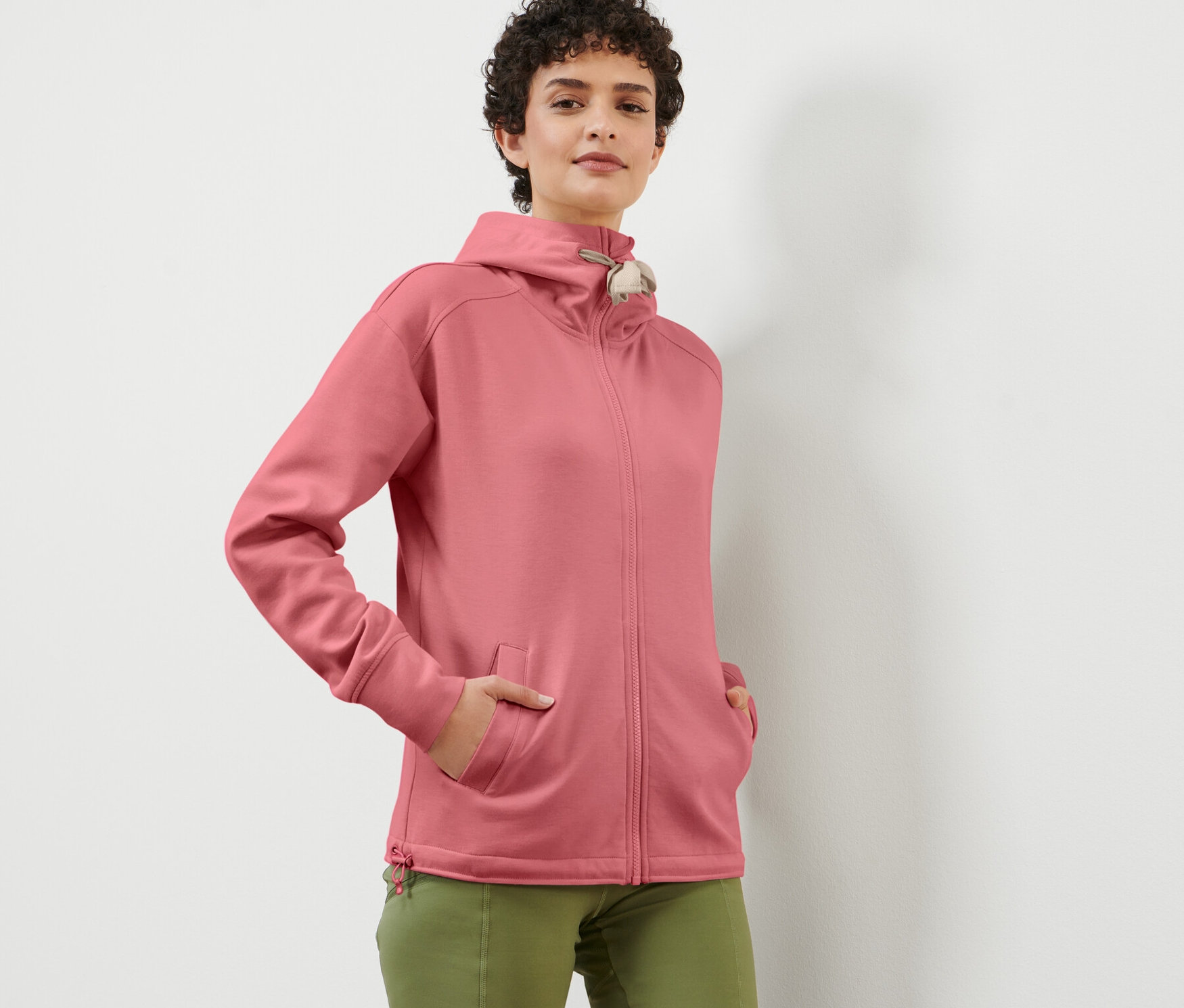 Frau posiert in einer roséfarbenen Kapuzen-Sweatjacke.