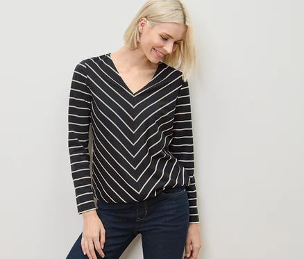Frau trägt ein gestreiftes Blusenshirt aus Modal-Mix und Jeans.
