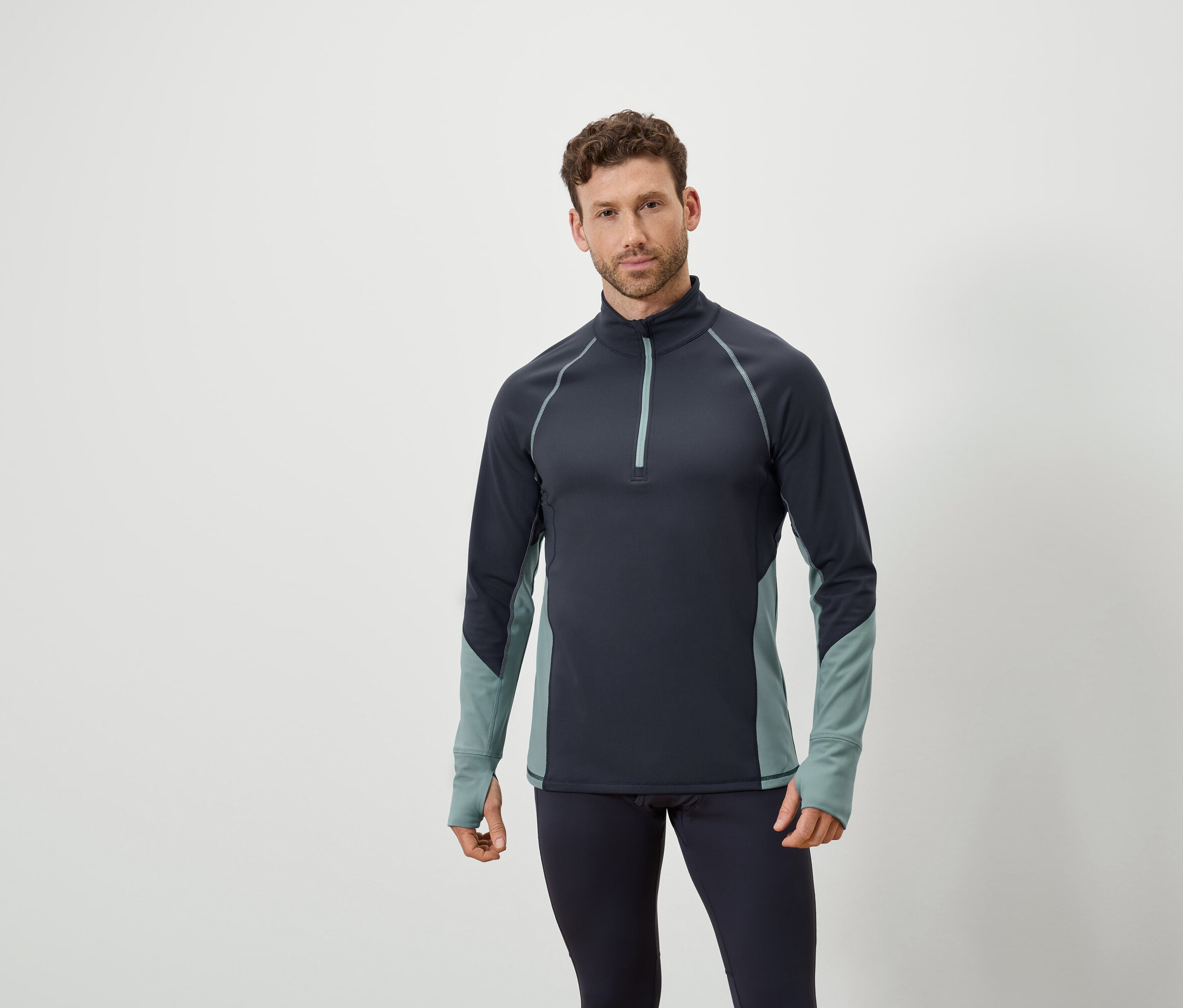 Mann posiert in marineblauem Langarmshirt mit Reißverschluss und marineblauen Leggings.