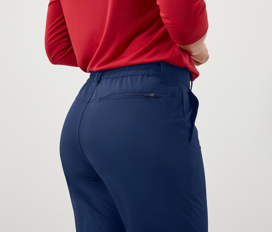 Eine Frau mit dem Rücken zur Kamera trägt ein rotes Langarmshirt und eine blaue Hose.