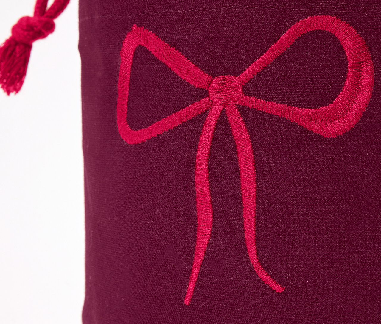 Detailaufnahme einer bordeauxfarbenen Geschenktüte mit roter Schleife.