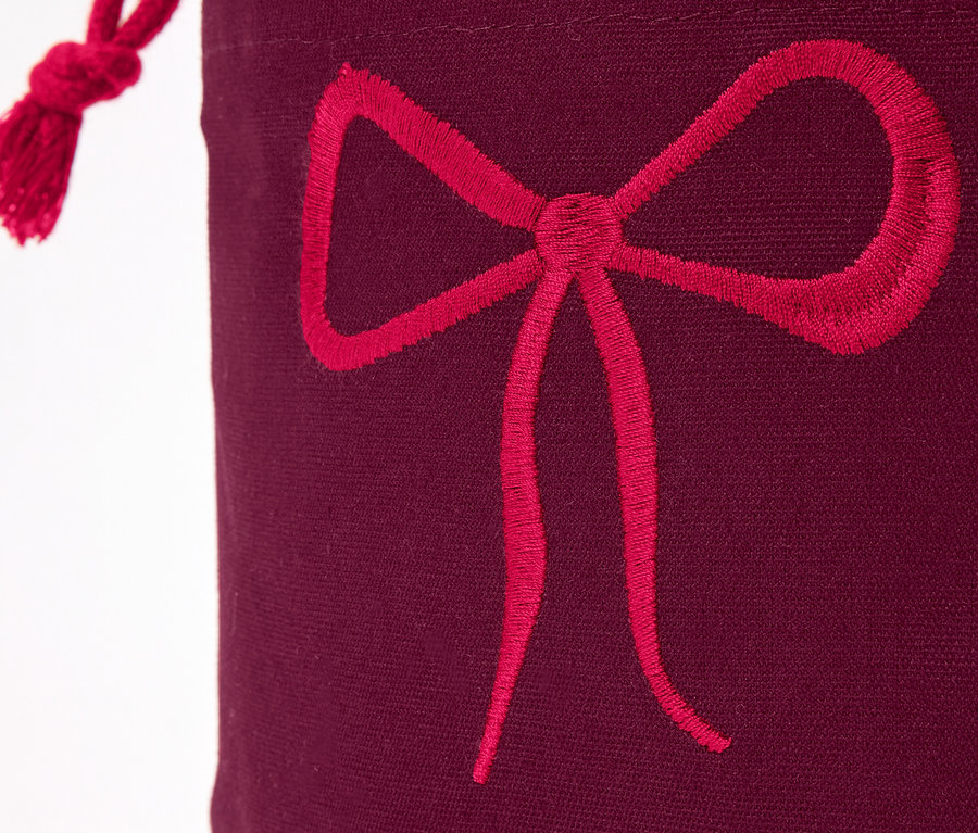 Detailaufnahme einer bordeauxfarbenen Geschenktüte mit roter Schleife.
