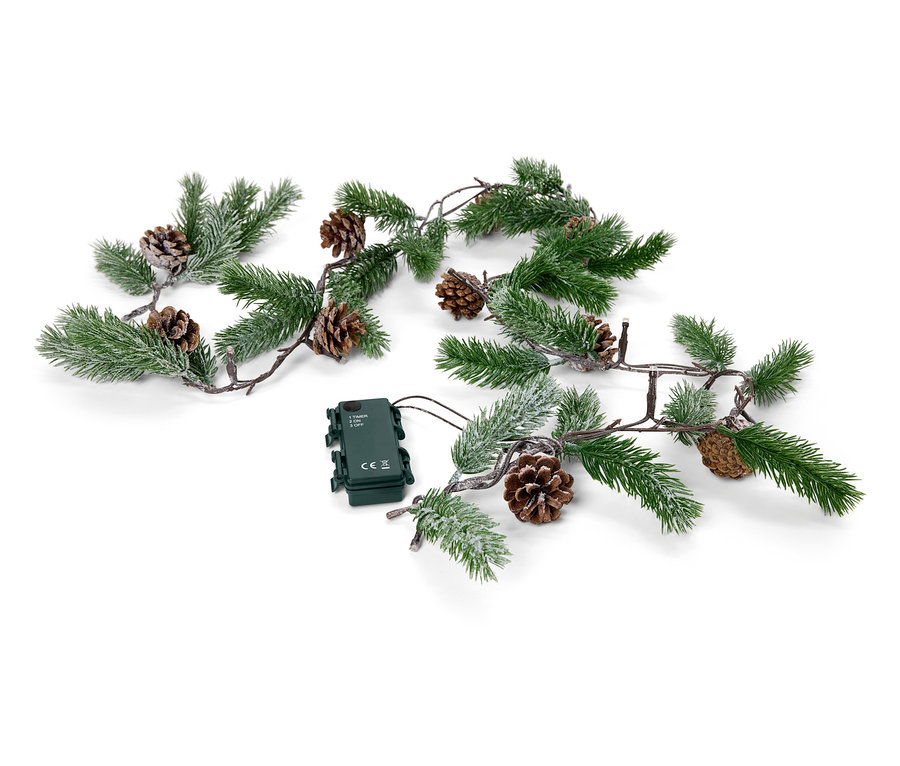 Eine grüne Girlande mit Tannenzapfen und einem Batteriefach liegt auf einem weißen Hintergrund.
