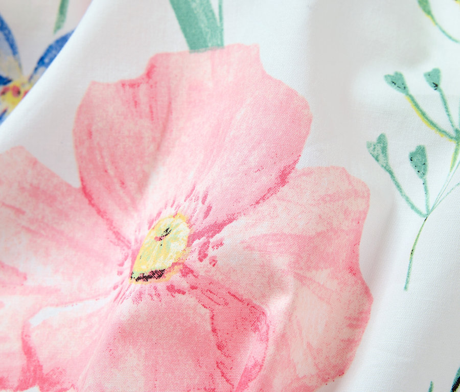 Detailaufnahme eines weißen Stoffes mit Blumenmuster, dominiert von einer großen rosa Blüte.