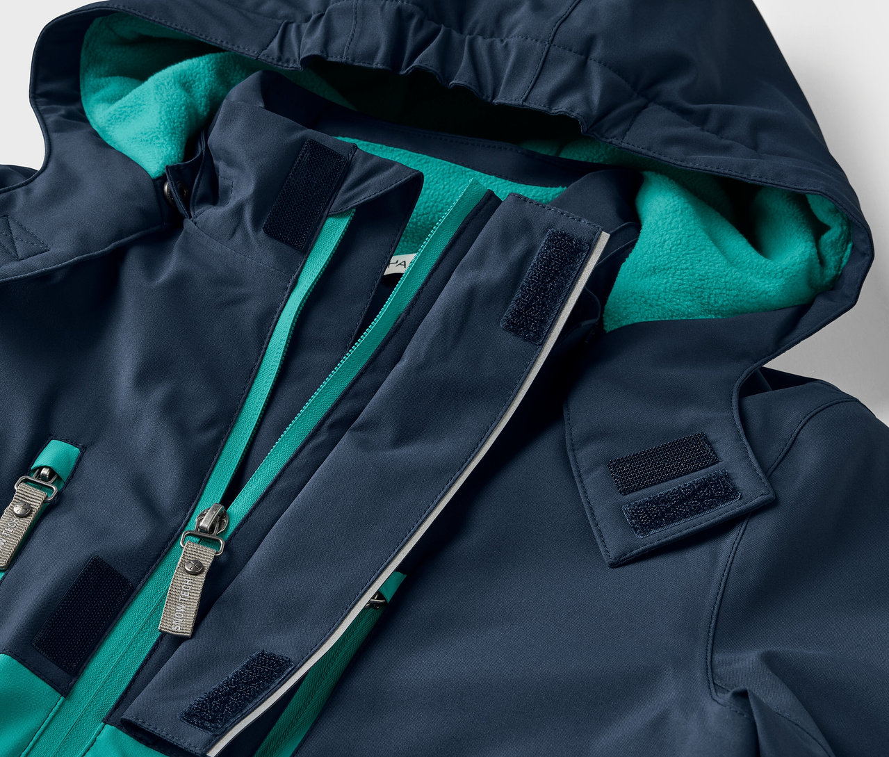 Detailaufnahme einer marineblauen Jacke mit Kapuze und grünem Reißverschluss.