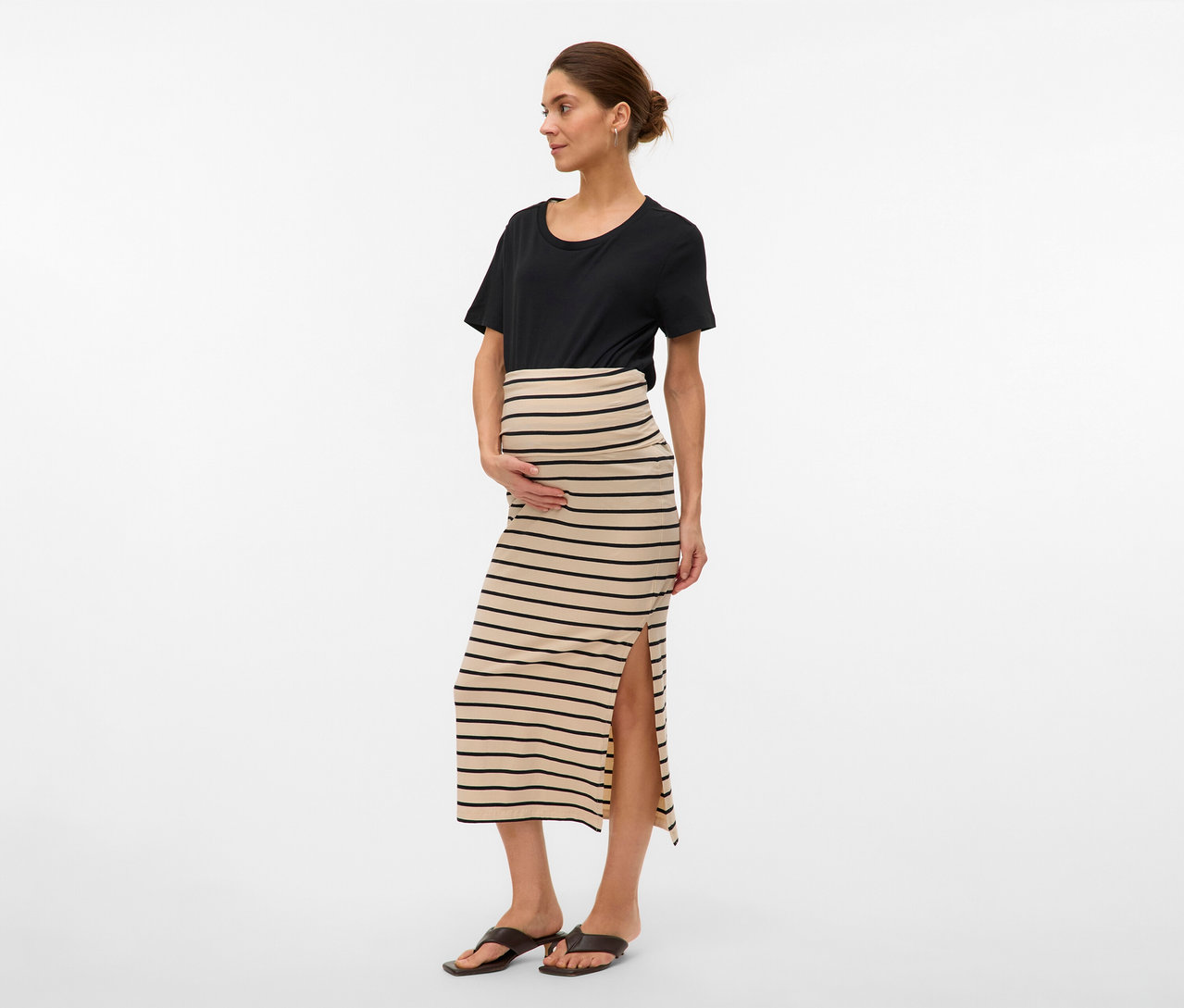 Frau mit schwarzem T-Shirt und gestreiftem MAMALICIOUS Maxirock »MLEVA« mit Schlitz. Sie hält ihre Hände auf ihren Bauch.