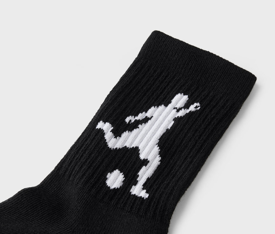 Nahaufnahme einer schwarzen Socke mit einer weißen Silhouette eines Fußballspielers, der einen Ball tritt.