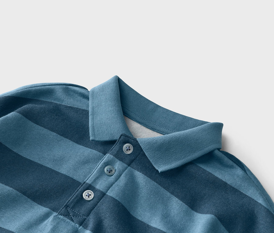 Nahaufnahme eines blau gestreiften Poloshirts mit drei Knöpfen am Kragen.