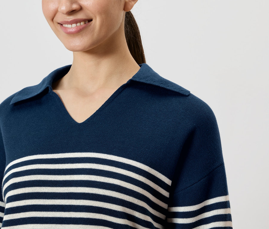 Lächelnde Frau trägt dunkelblaues, gestreiftes Poloshirt mit Kragen.