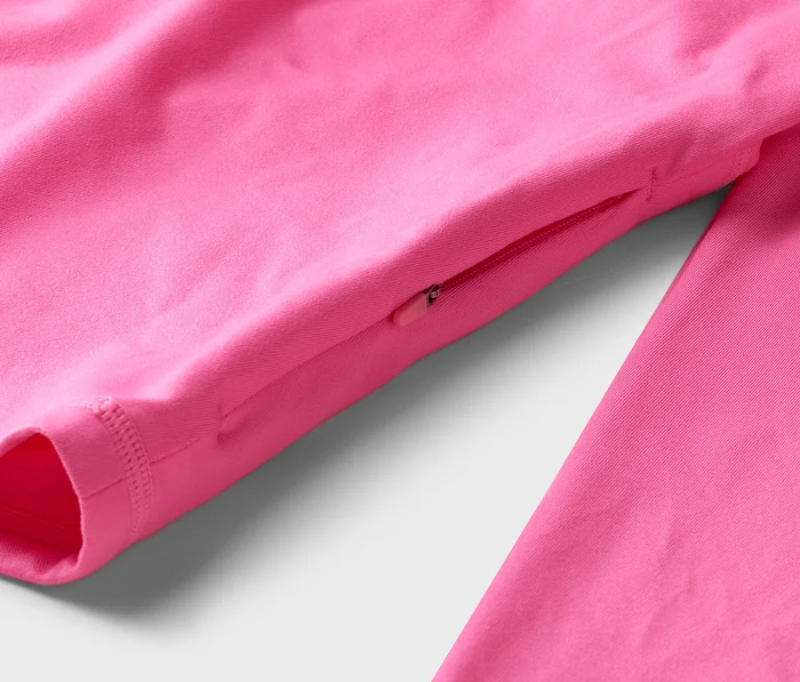 Nahaufnahme eines pinkfarbenen, langärmeligen Oberteils mit Reißverschlusstasche am Ärmel.