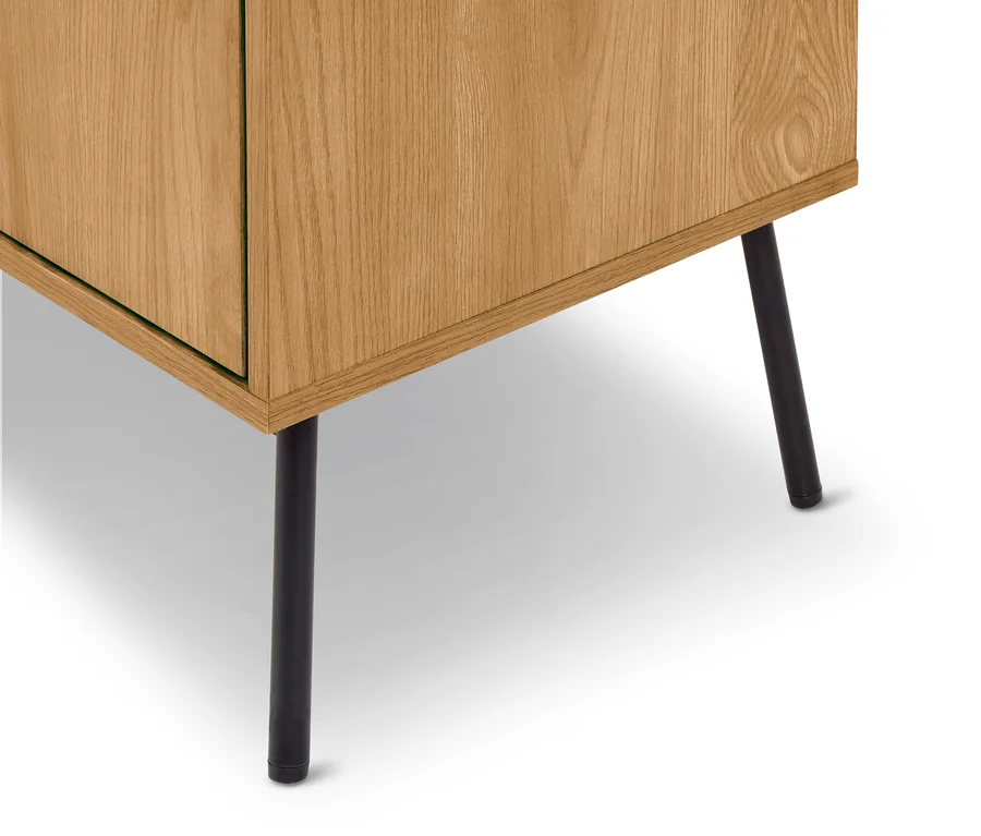 Untere Ecke eines hellen Holzschranks mit zwei schwarzen Metallbeinen auf weißem Hintergrund.