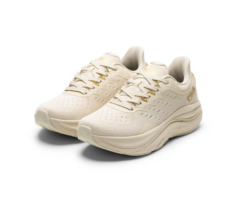 Zwei cremefarbene FILA Retron Damen-Sneaker mit goldenen Akzenten und dicken Sohlen stehen auf weißem Hintergrund.