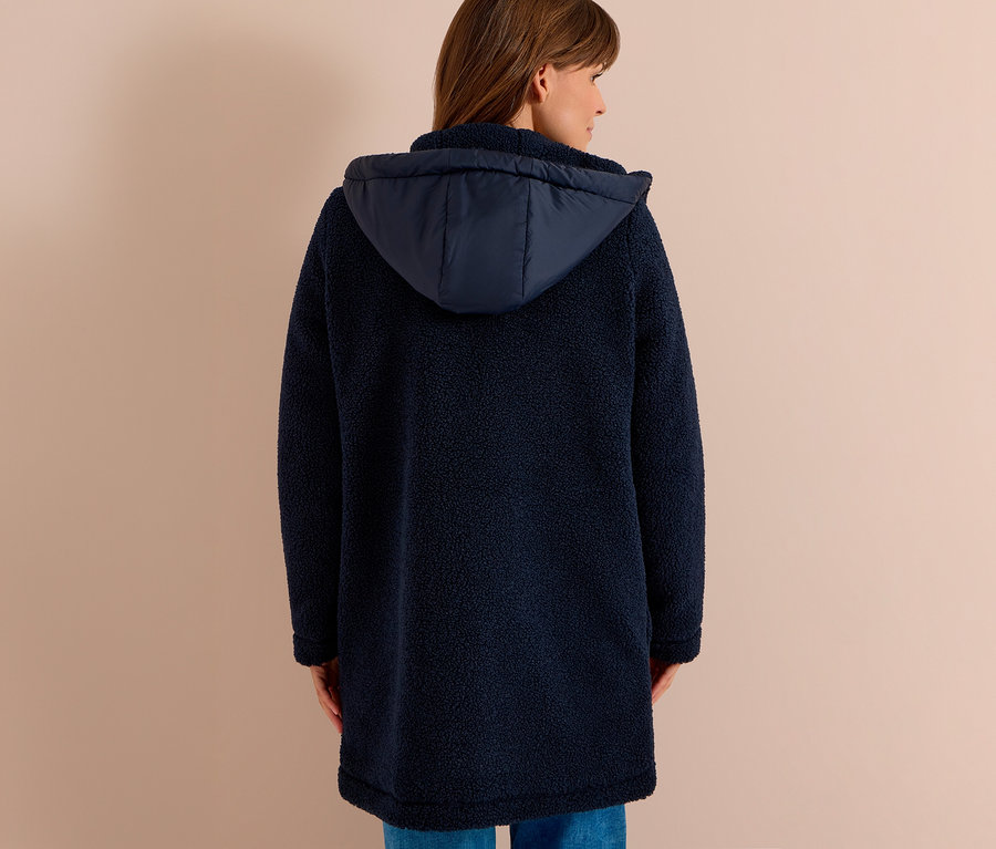 Frau von hinten in einer langen, marineblauen CECIL Jacke aus Teddyfleece mit Kapuze und blauen Jeans.