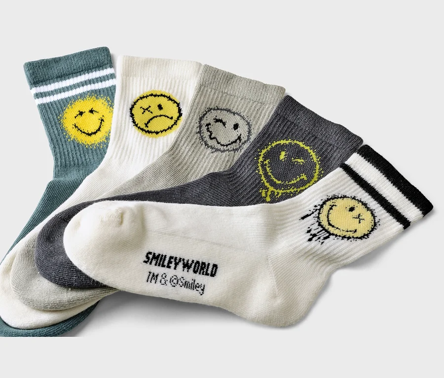 Fünf Socken in Grün, Weiß, Grau und Anthrazit mit Smileyworld-Motiven liegen übereinander.