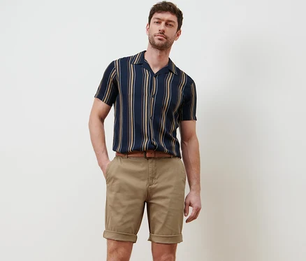 Mann posiert in beigen Chino-Shorts.