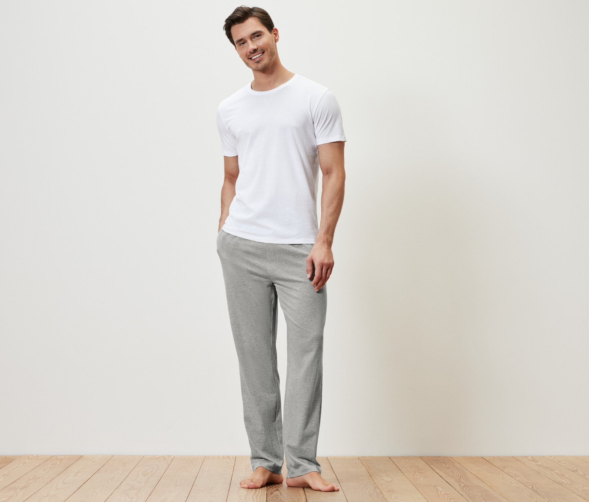 Mann trägt ein weißes T-Shirt und eine graue Relaxhose.
