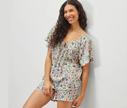Frau posiert in einem Shorty-Pyjama-Set mit Blumenmuster.