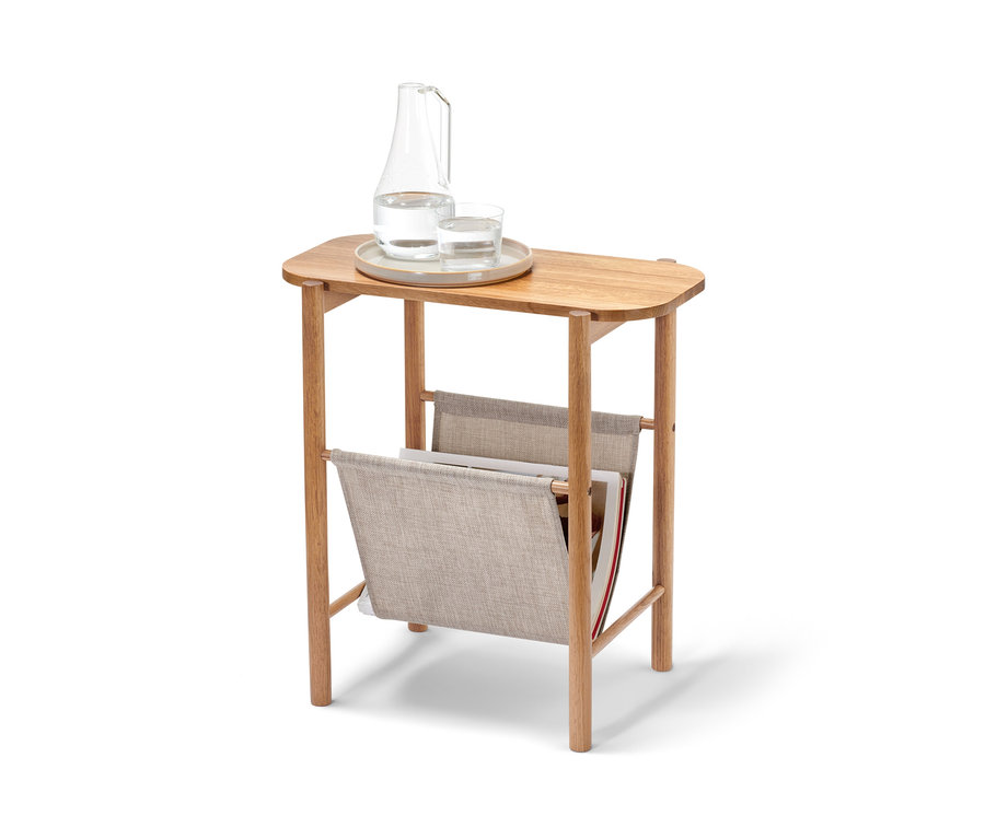 Auf einem Beistelltisch mit Schlaufenablage stehen eine Karaffe und ein Glas Wasser.