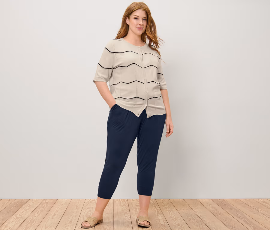 Frau posiert in Feinstrick-Cardigan mit Ajour-Muster und 3/4-Jerseyhose.