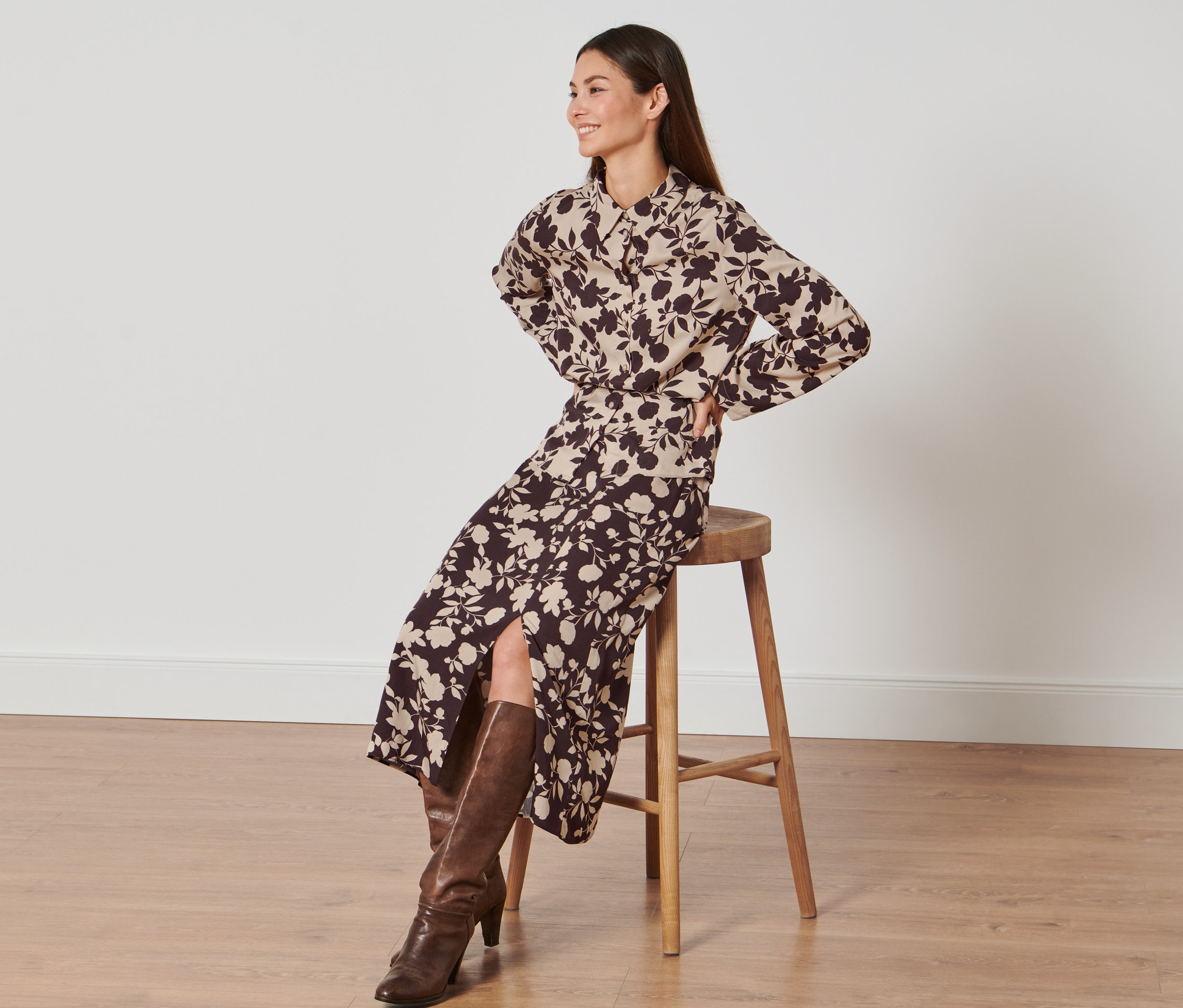 Frau sitzt auf einem Hocker und trägt einen Rock mit Alloverprint.