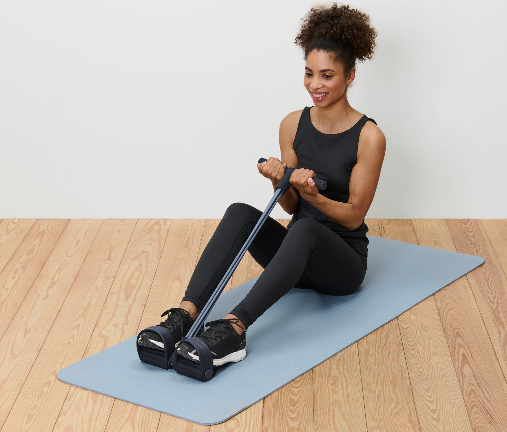 Frau sitzt auf einer Matte und benutzt einen Bauch-und-Rückentrainer.