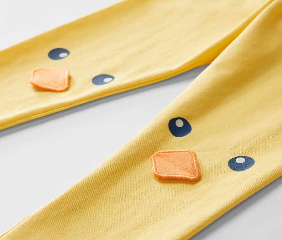 Detailansicht von gelben Kinderleggings mit Küken-Motiv.