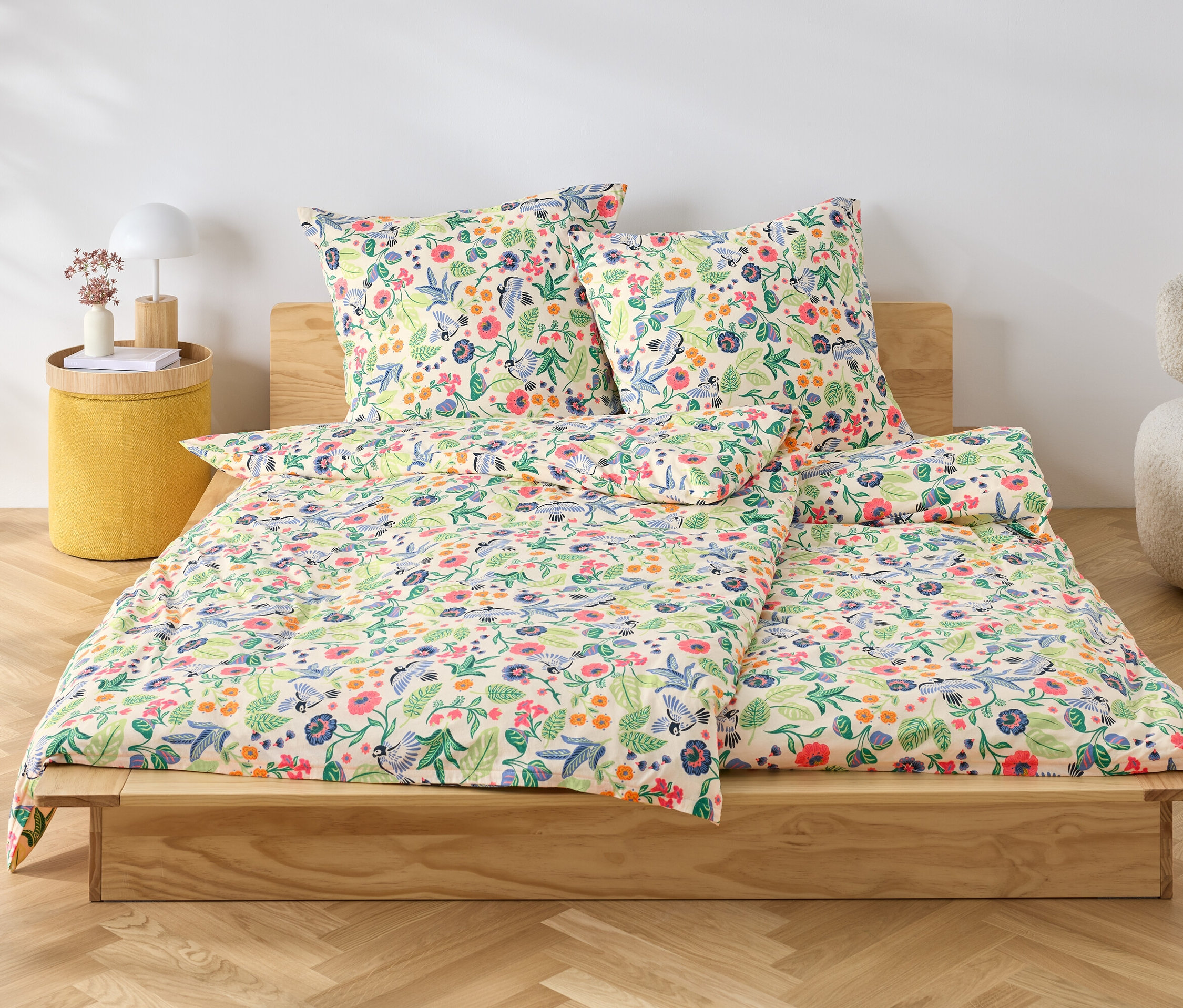 Blumige Jersey-Bettwäsche liegt auf einem Holzbett.