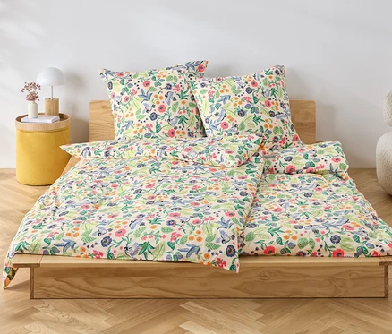 Blumige Jersey-Bettwäsche liegt auf einem Holzbett.