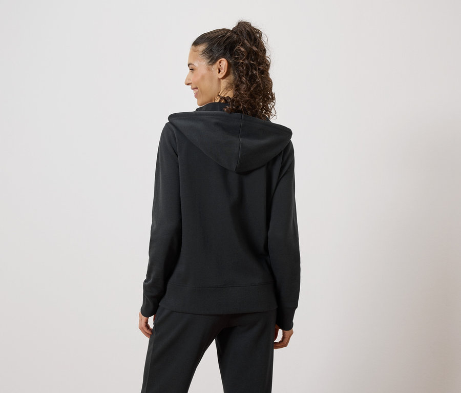 Frau von hinten, die einen schwarzen Hoodie und eine Jogginghose trägt.