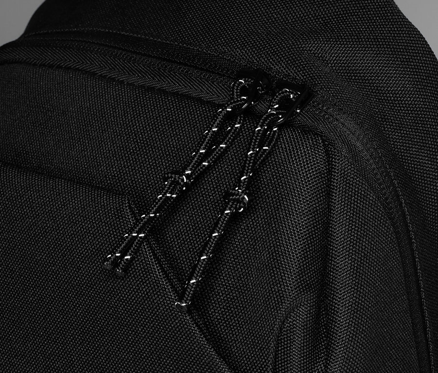 Detailaufnahme eines schwarzen Rucksacks mit Reißverschluss und Kordelzug.
