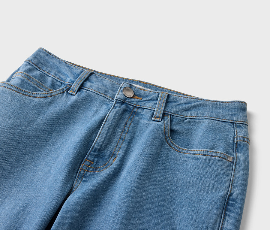 Nahaufnahme einer hellblauen Jeans mit Taschen, Gürtelschlaufen und einem silberfarbenen Knopf.