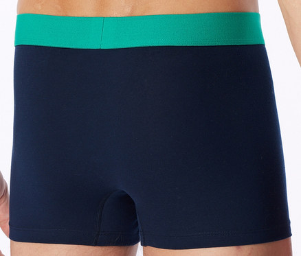 Person trägt dunkelblaue Boxershorts mit einem leuchtend grünen Bund.