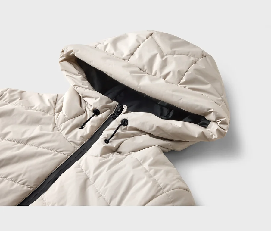 Helle, gesteppte Jacke mit Kapuze, schwarzem Reißverschluss und schwarzen Kordelzügen.