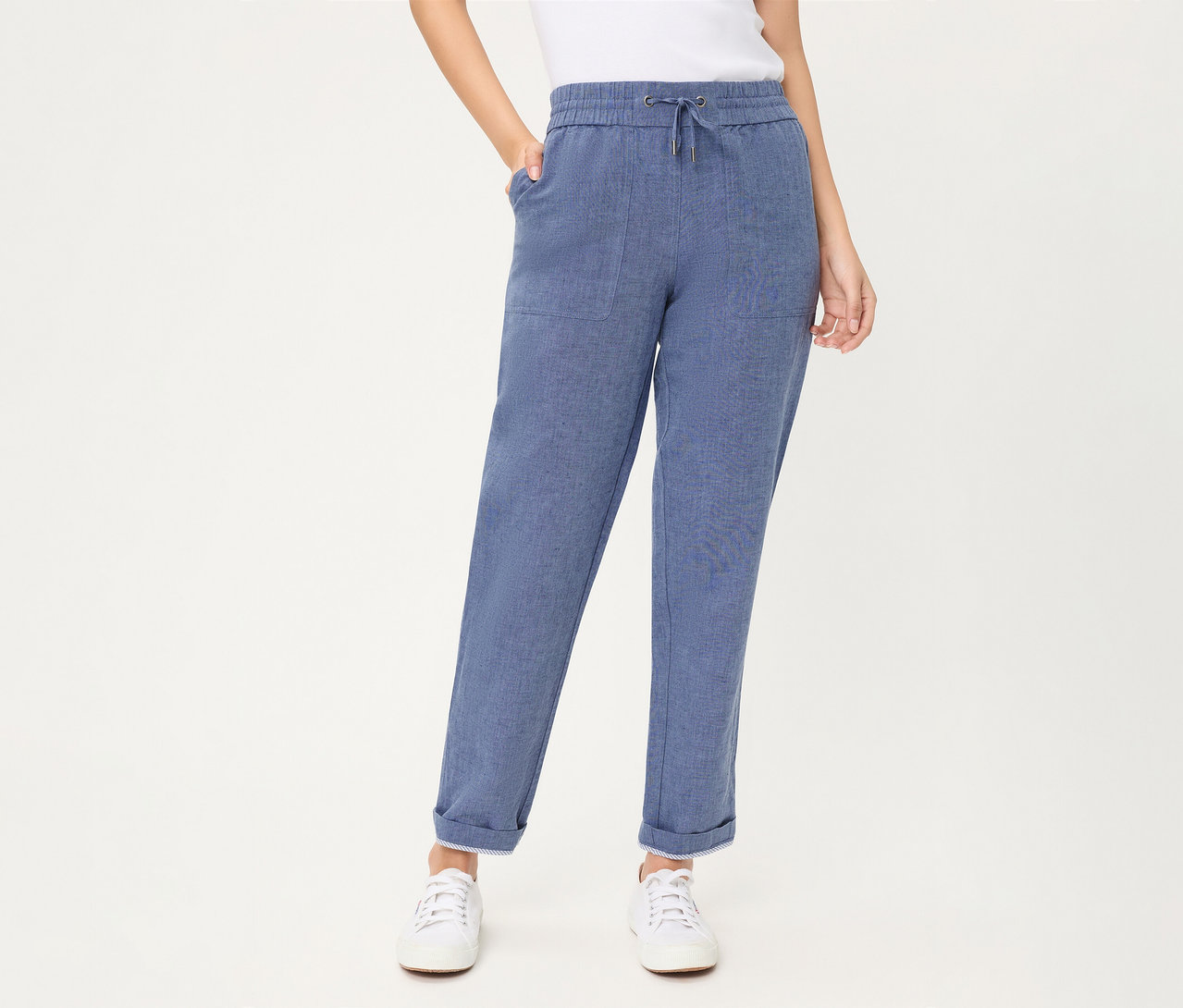 Eine Person trägt eine blaue Olsen Cropped Jeans mit Kordelzug, aufgesetzten Taschen und umgekrempelten Säumen, dazu weiße Sneaker.