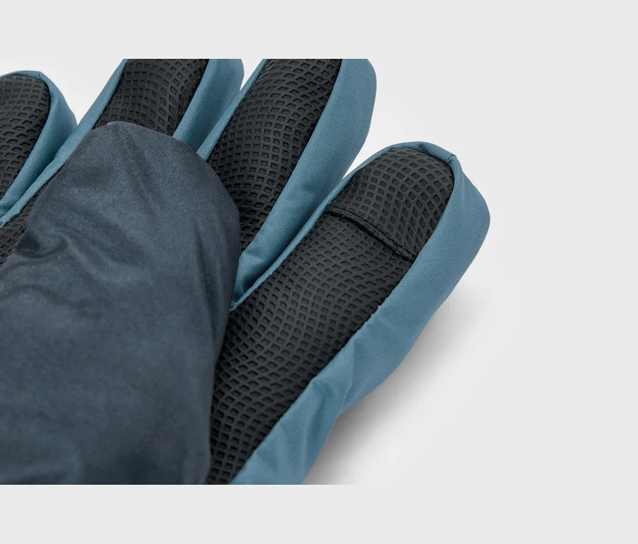 Nahaufnahme eines dunkelblauen und türkisfarbenen Handschuhs, der die Handfläche mit schwarzem, strukturiertem Griffmaterial an den Fingerspitzen und der Handfläche sowie glattem Stoff auf dem Handrücken zeigt.