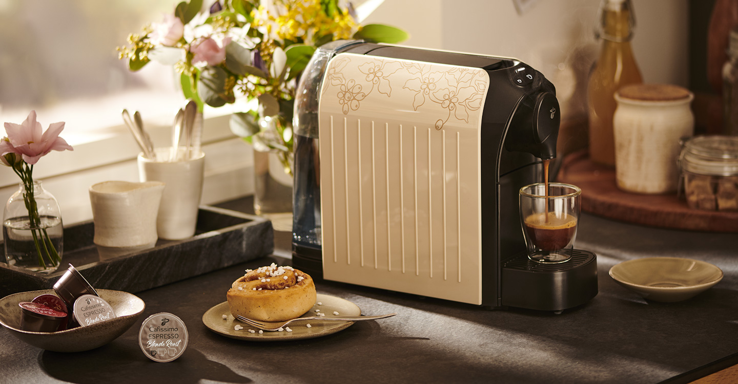 Cafissimo easy in Light Beige steht auf einer Küchentheke, daneben die beiden Packungen der Cafissimo Blonde Roast Edition