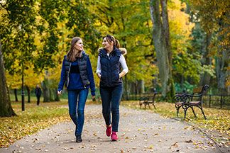 Gute Qualität für Ihre Sportweste: Zwei Frauen spazieren durch einen herbstlichen Park und unterhalten sich. Beide tragen schwarze Sportwesten.