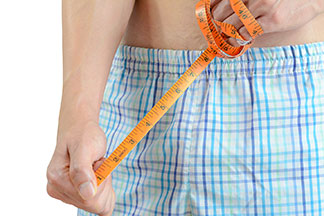Nahaufnahme eines Mannes, der eine Boxershorts trägt, und ein Massband in der Hand hält.