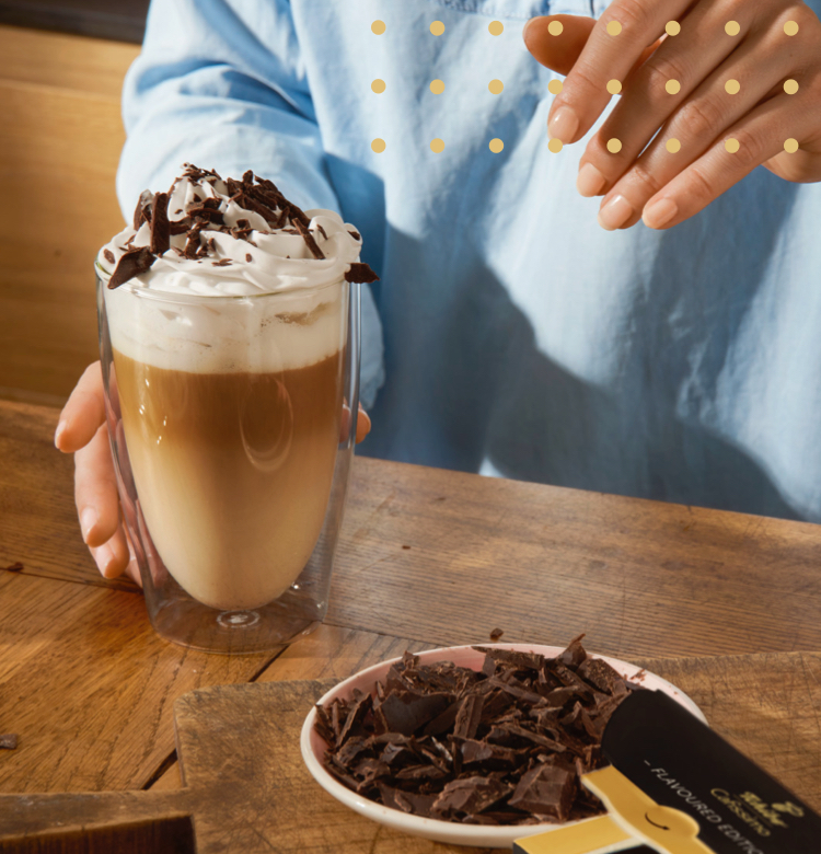 Eine Frau giesset einen Espresso in ein Latte Macchiato Glas, um einen Double Chocochiato zuzubereiten