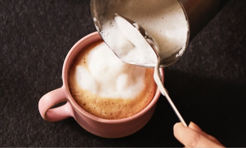 Milchschaum in Tasse giessen
