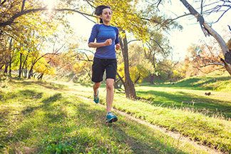 Eine junge Frau joggt in Sportshorts im Herbst durch einen Park.