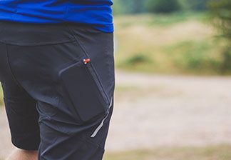 Nahaufnahme einer schwarzen Sportshorts mit den Umrissen eines Smartphones in der Reissverschlusstasche.