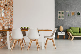 Ein modern eingerichtetes Wohnzimmer mit einem Esstisch, an dem weisse Schalen-Stühle mit hellen Holzbeinen stehen.