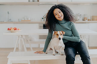 Sitzbank als Mittelpunkt der Küche: Eine junge Frau sitzt mit ihrem Hund auf einer weissen Sitzbank in der Küche.