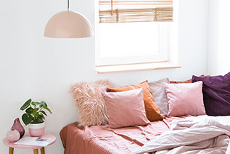 Kopfkissenbezüge sorgen für Gemütlichkeit: Ein Bett mit vielen quadratischen Kissen in unterschiedlichen Grössen und Farben.